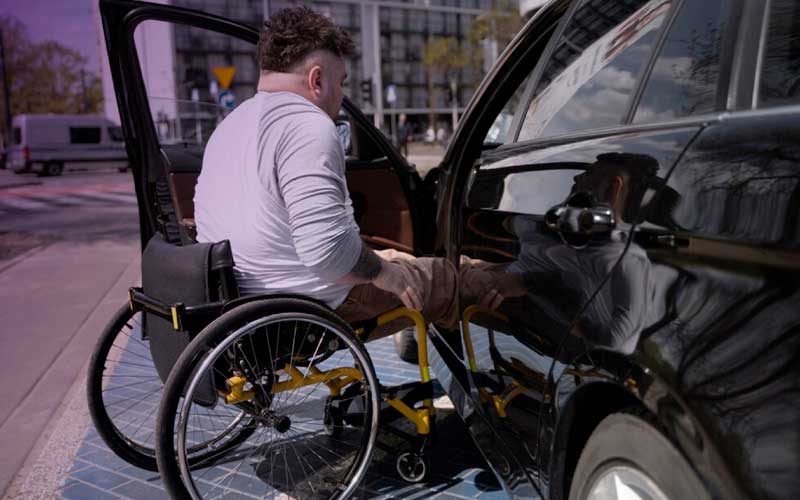 Hombre en silla de ruedas a punto de entrar a un auto.